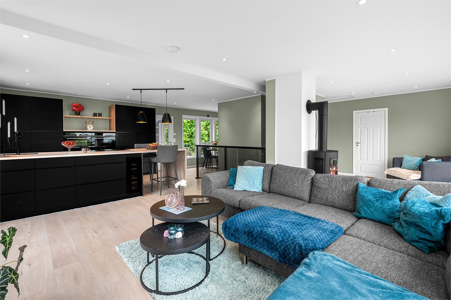 Det åpne stue/kjøkkenarealet føles likevel tilbaketrukket med sine egne soner og plasseringer. Legg spesielt merke til downlights i taket som er plassert rundt om i hovedplanet. 