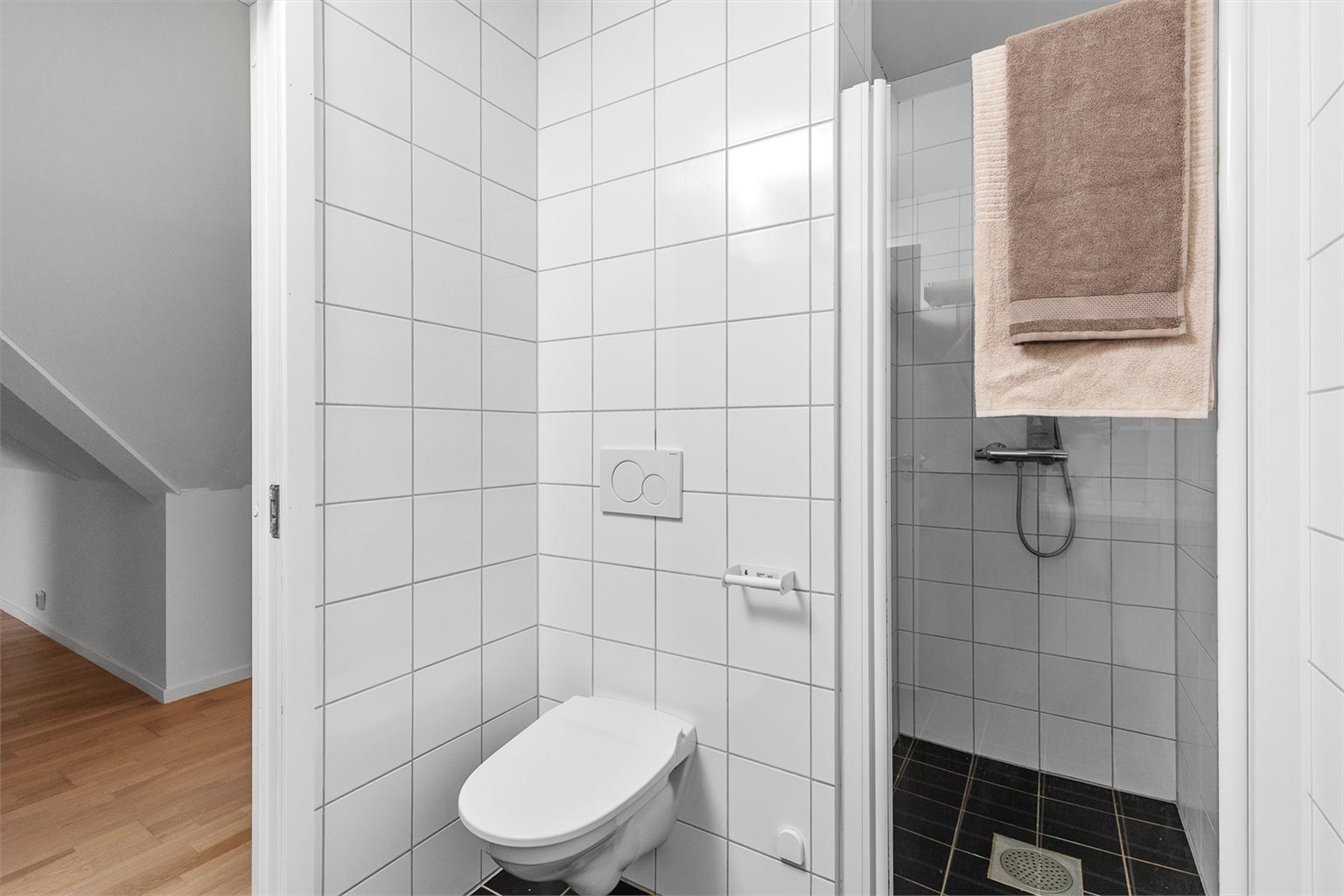 Badet er innredet med dusjdør av glass, vegghengt do, innredning med servant og opplegg for vaskemaskin.