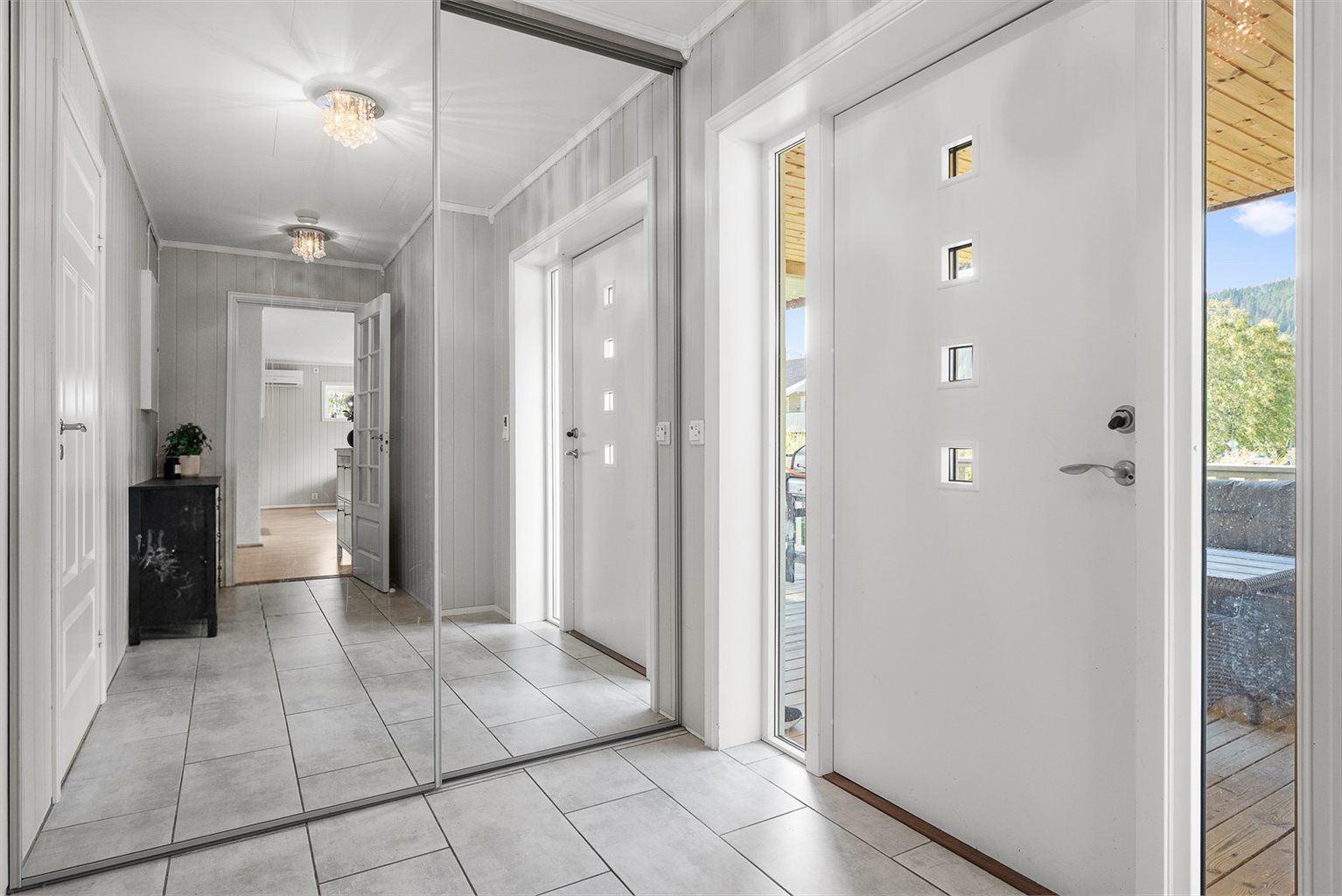 Gangen er en del av tilbygget i 1. etasje, og byr på en innbydende entré på ca. 9,5 kvm med flislagt gulv og praktisk skyvedørsgarderobe med speilfronter.