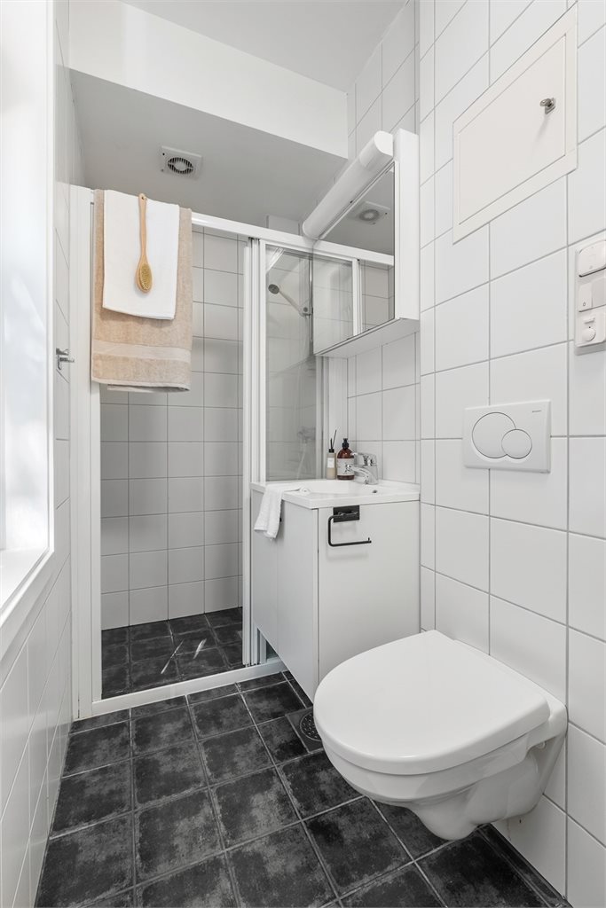 Effektivt bad på 3,8 m² med dusjkabinett og servant med underskap.