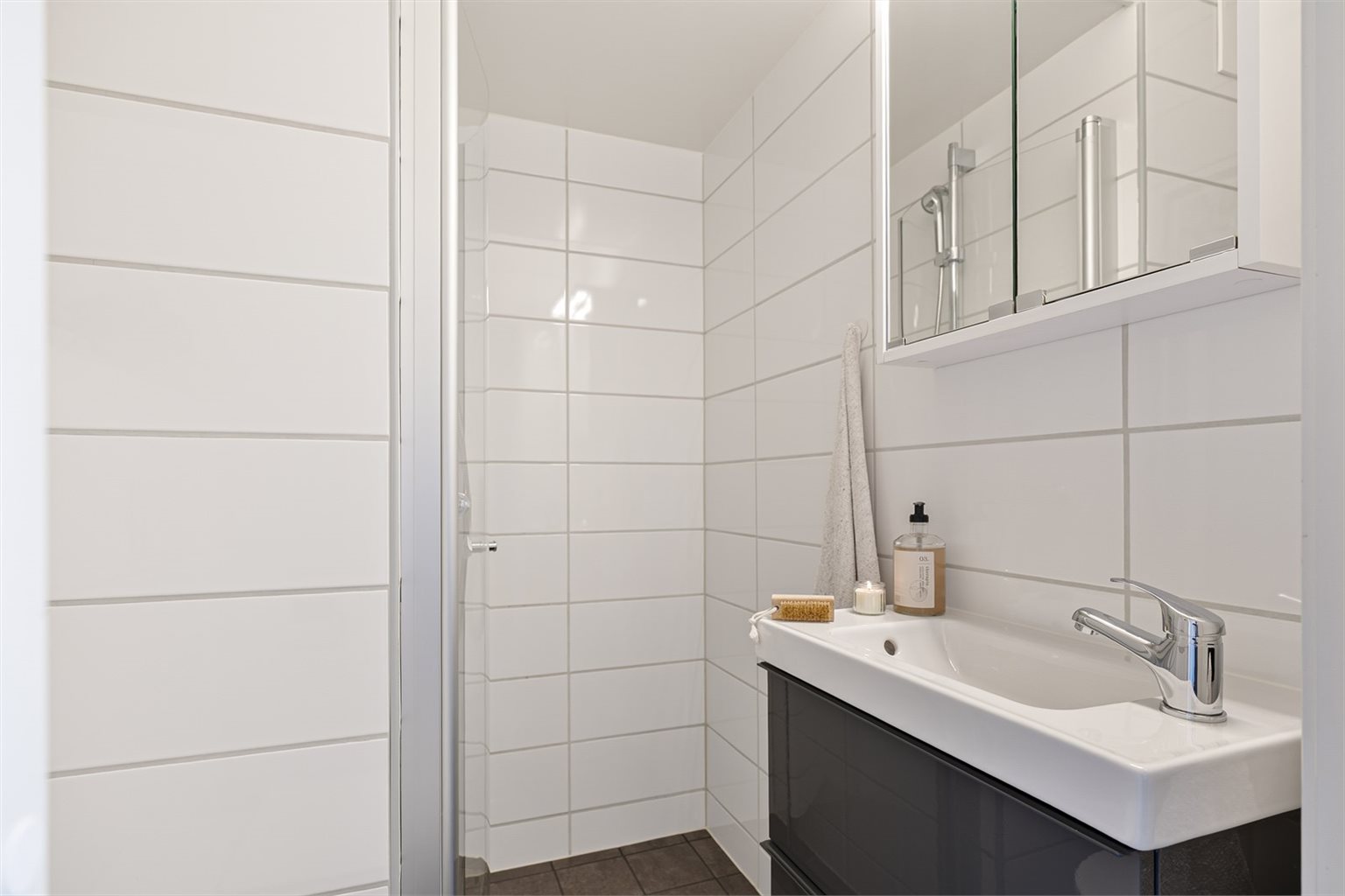 Badet er flislagt og byr på vegghengt servant med TG1 fra takstmann og praktiske innfellbare dusjdører.