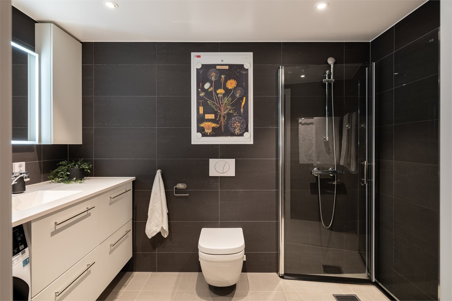 Videre er badet påkostet med blant annet  300X600 veggfliser, benkeplate med nedfelt vask og oppgardert toalett med hygienecoating.