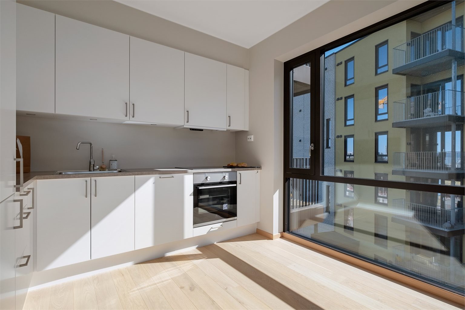 Kjøkkenet byr på integrerte hvitevarer som stekeovn, platetopp, oppvaskmaskin, kombiskap og mekanisk avtrekk over stekesone. Det er også montert spotlights på undersiden av overskapene for elegant belysing.