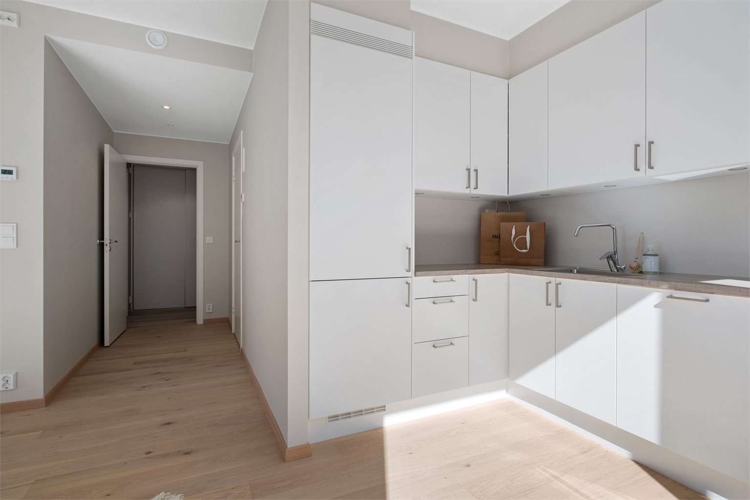 Leilighetens gode og smarte planløsning i kombinasjon med lekre farge- og materialvalg bidrar til en god atmosfære. Her får du beige detaljer på kjøkken, vegger malt i beige samt lekker 1-stavs eikeparkett. 