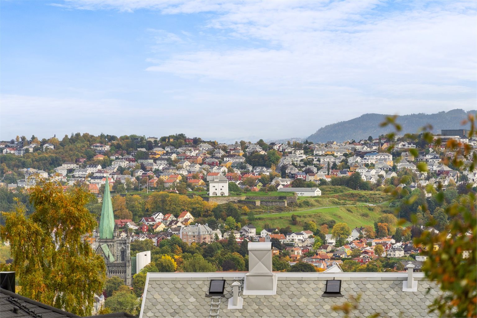 Bredt utsyn over Trondheim, med Fosenalpene på andre siden av fjorden i nordvest og Nidarosdomen og Kristiansten festning i øst.