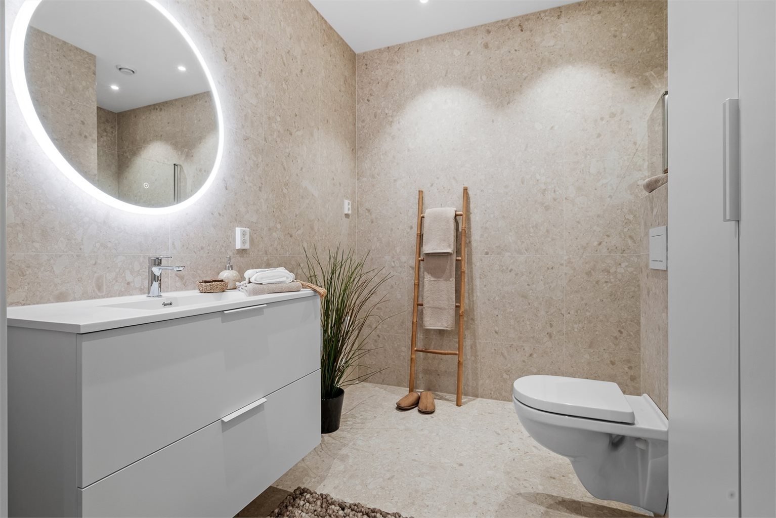Badet har flislagte vegger og gulv med varmekabler, vegghengt wc, tidløs innredning og dusjhjørne. Det er i tillegg opplegg for vaskemaskin på badet.