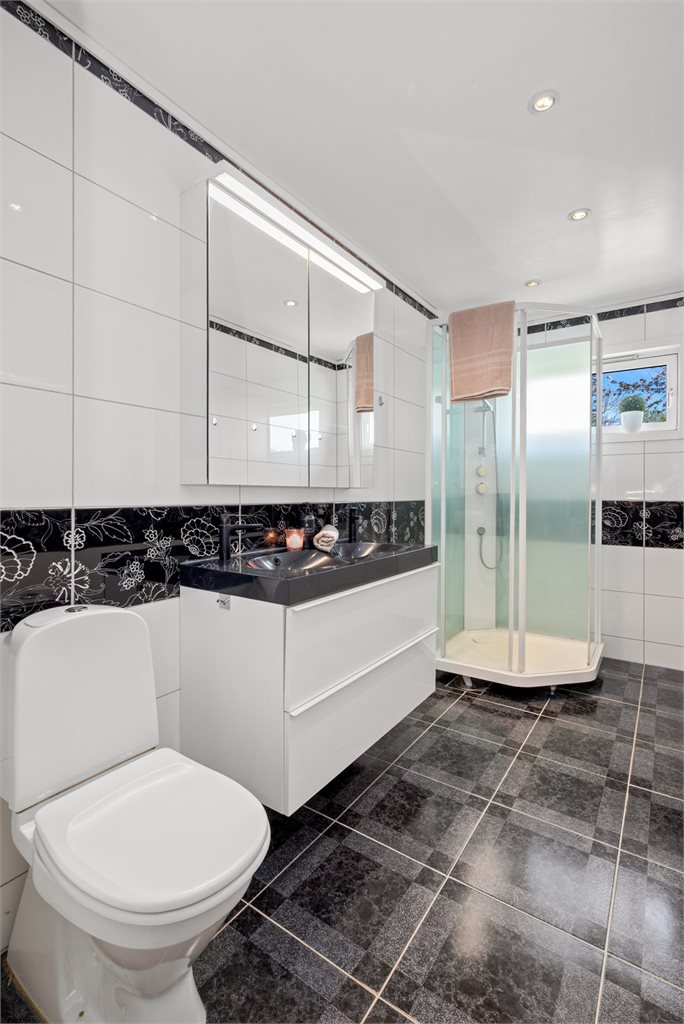 Videre finner vi etasjens bad, som byr på flis på gulv og vegger. Malt overflate i himling og gulvvarme. Badet er utstyrt med dusjkabinett, servantskap, wc og opplegg for vaskemaskin.
 
