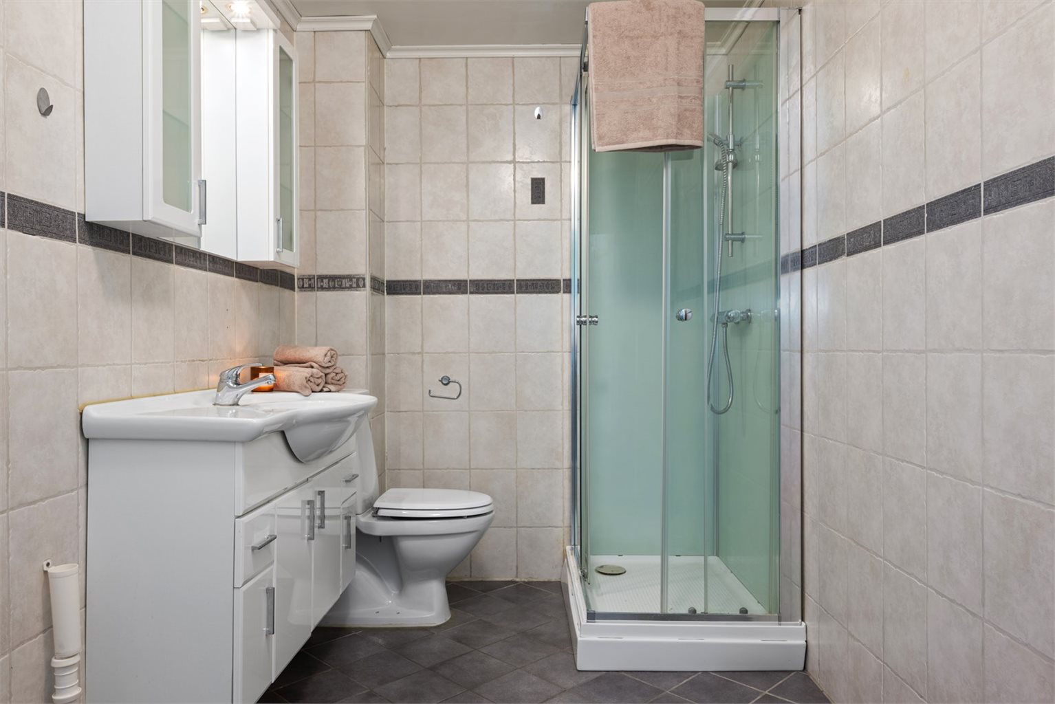 Utleiedelen har et smart innredet bad på 6,5 kvm. Badet er utstyrt med dusjkabinett, servantskap, wc og opplegg for vaskemaskin.